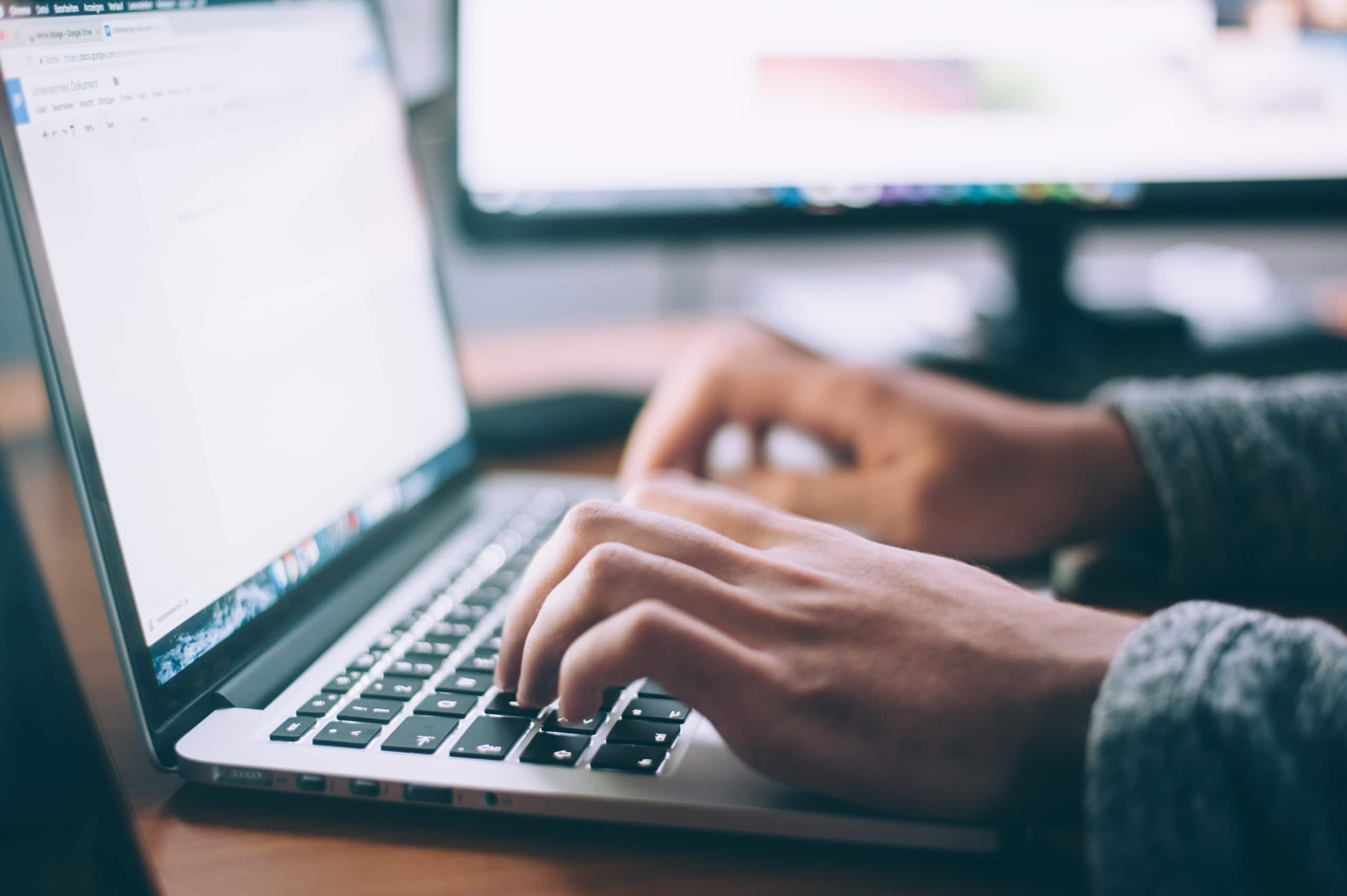 close-up view of someone's hands typing on a laptop keyboard