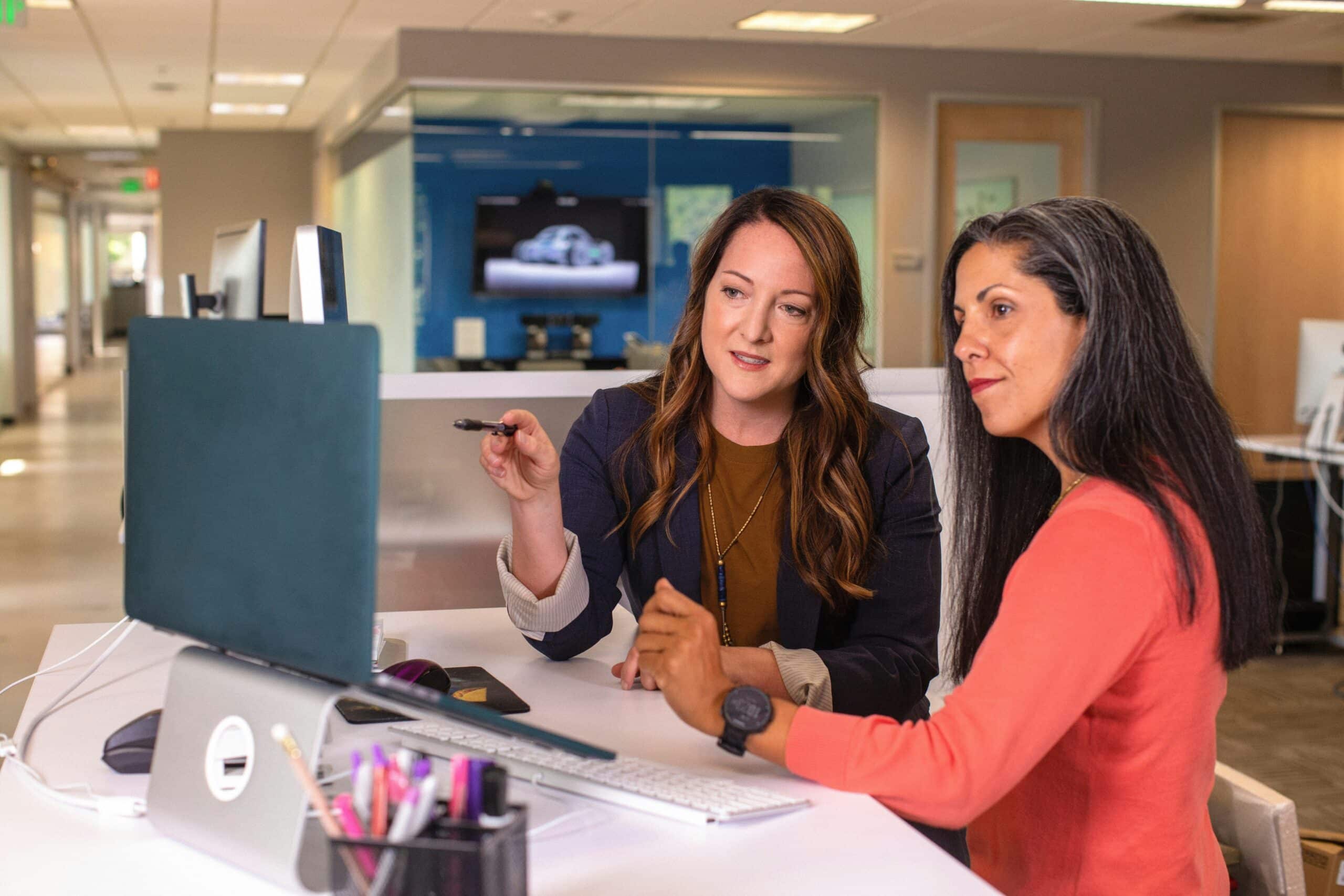 admissions leaders sit together at a desk and look at a laptop