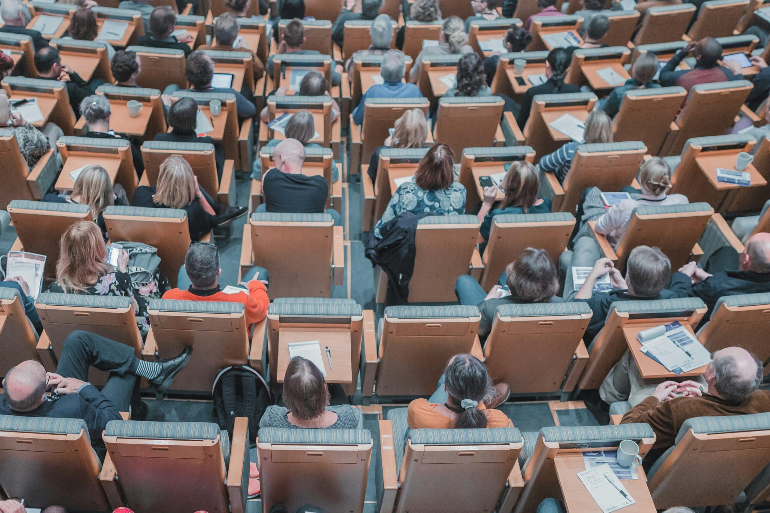 Aerial view of students sitting in a large conference room at university