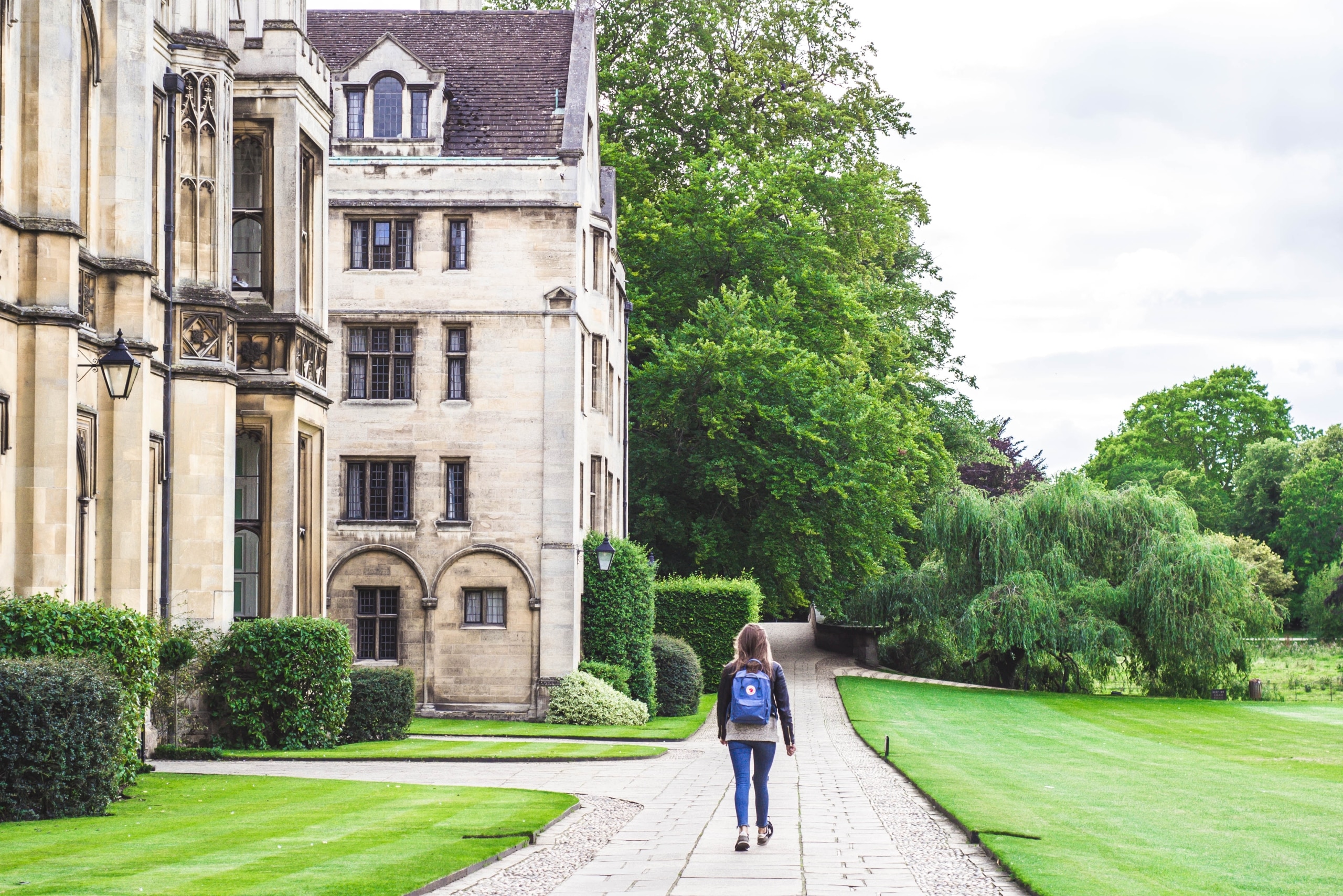 student walking next to a historical campus building